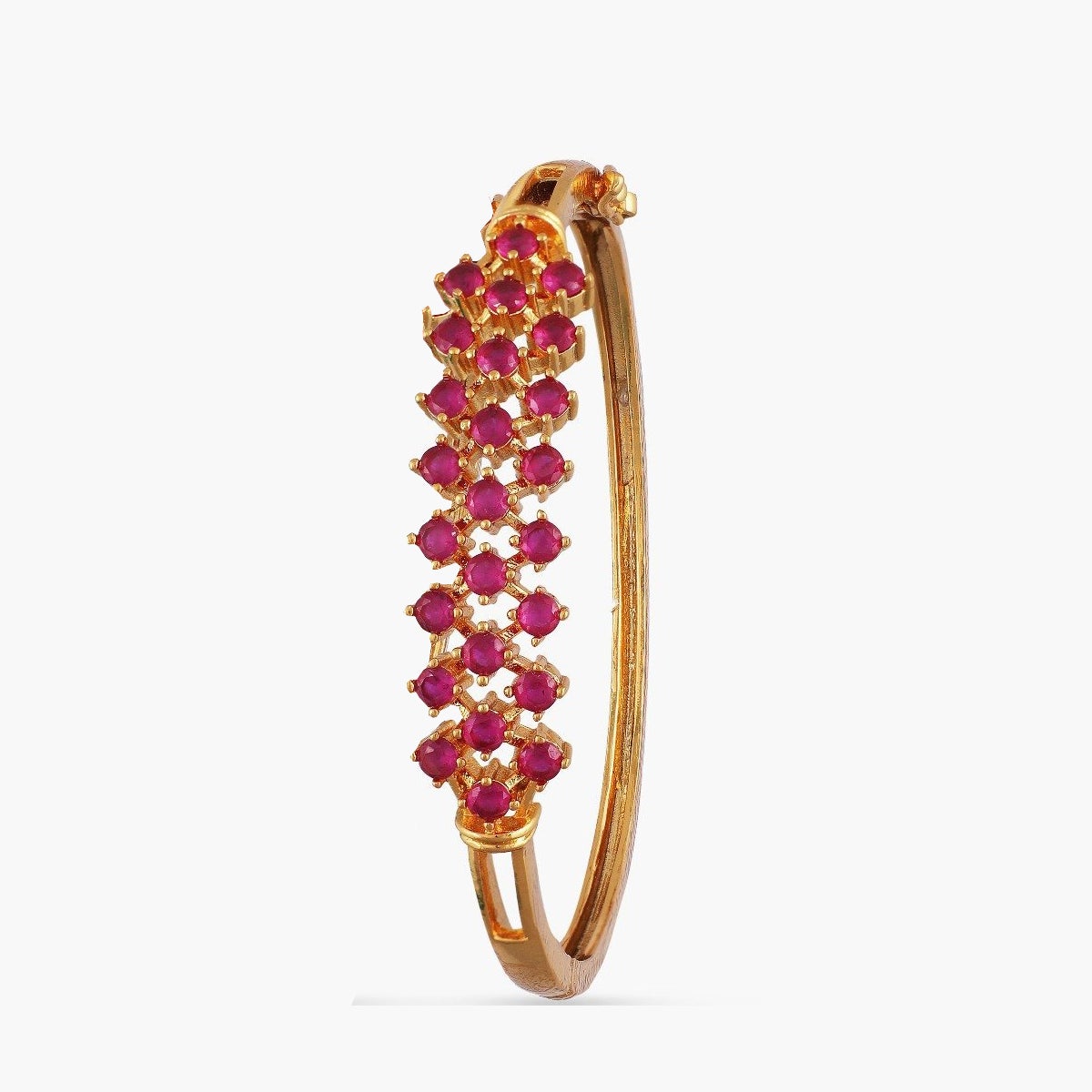 A picture of an Indian artificial bracelet: a gold colored bangle with red gemstones, on a white background. 
